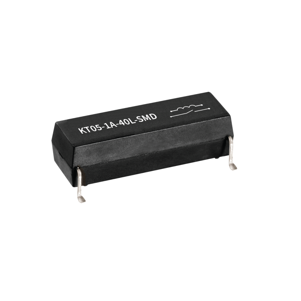 A black rectangular Reed Relay electronic component with four metal pins, labeled KT05-1A-40L-SMD and featuring a white inductor symbol on top, isolated on a white background. by Standex Detect