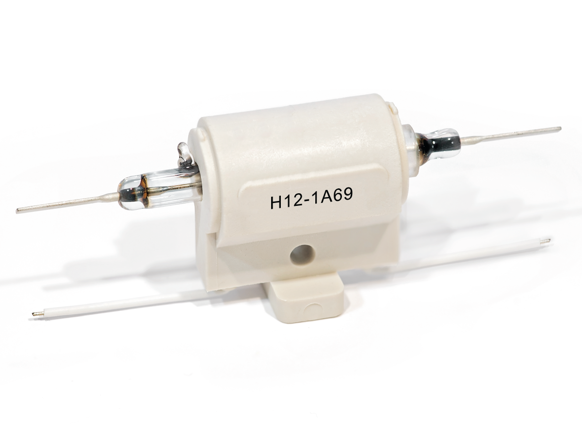 A white ceramic H Series Reed Relay electrical component labeled H12-1A69 with two metal terminal leads on each side and a mounting base underneath, isolated on a white background. by Standex Detect