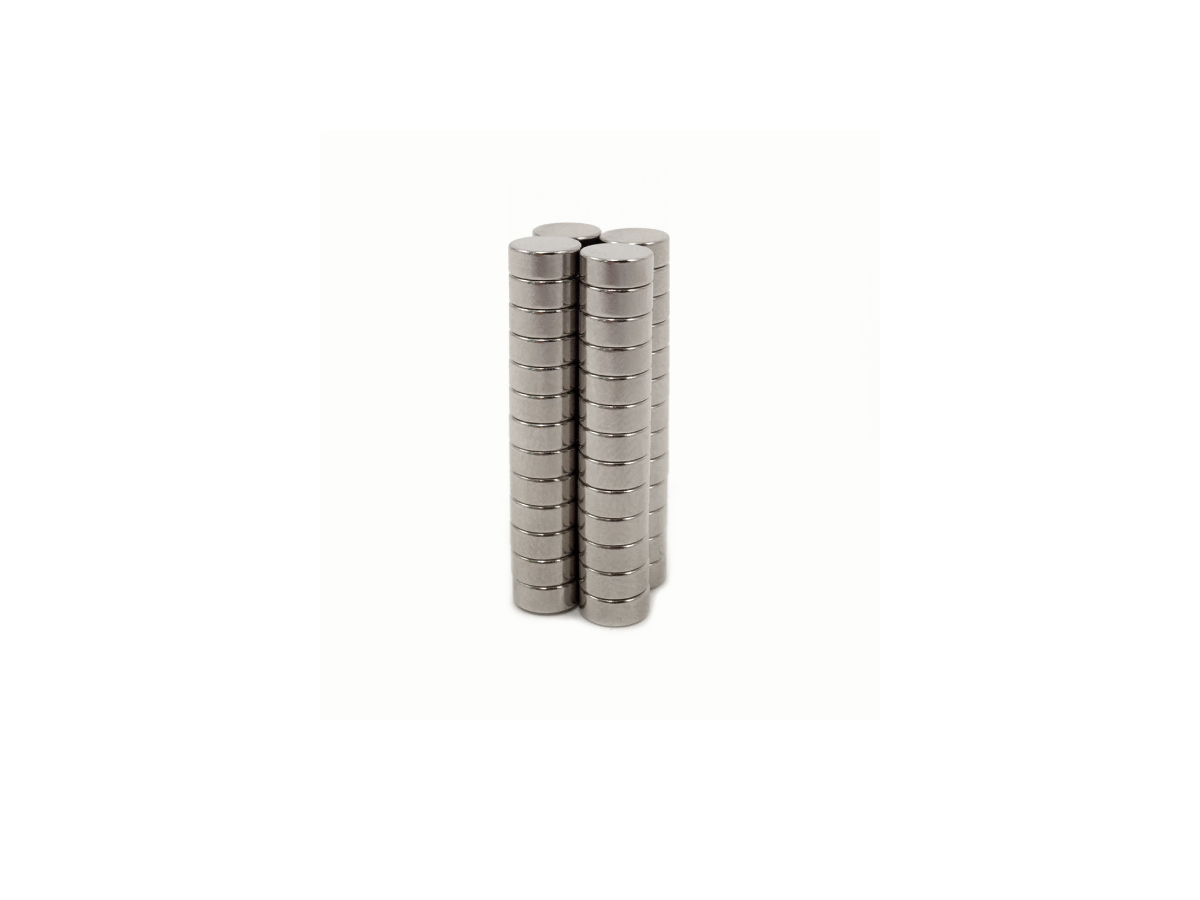 Two neat stacks of small, round NdFeB magnets stand upright side by side on a white background. by Standex Detect